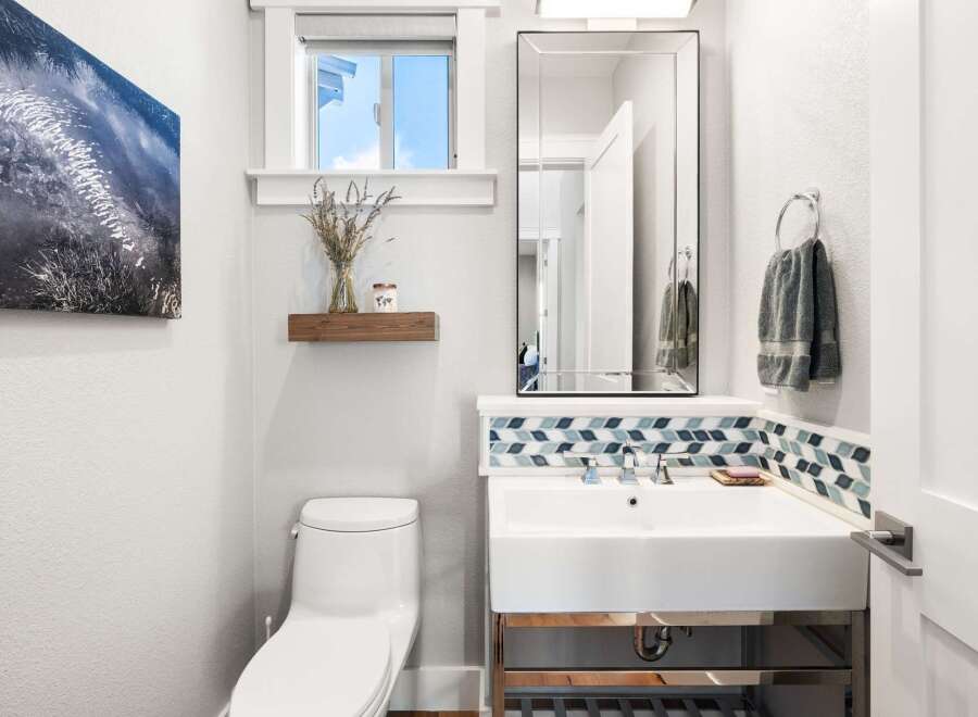This modern bathroom features a sleek white toilet and a stylish vanity with a vessel sink.