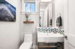 This modern bathroom features a sleek white toilet and a stylish vanity with a vessel sink.