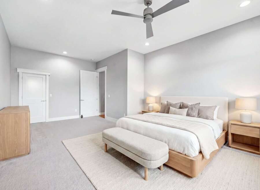 Experience modern comfort in this serene bedroom, featuring a plush king-sized bed adorned with elegant throw pillows and a cozy duvet.