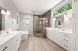 Experience luxury in this spacious master bathroom, featuring a freestanding soaking tub and a large, glass-enclosed walk-in shower with modern tilework.