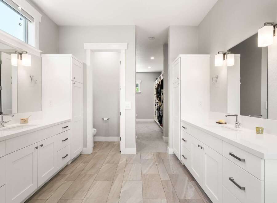 This spacious master bathroom features dual white vanities with modern chrome fixtures and ample storage.