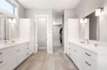This spacious master bathroom features dual white vanities with modern chrome fixtures and ample storage.