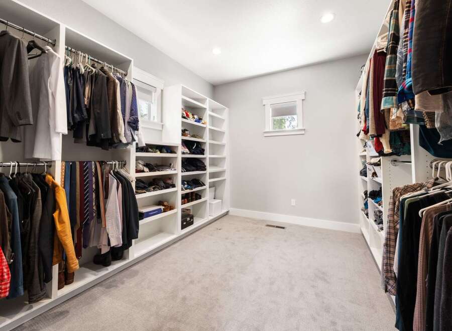 Step into this spacious walk-in closet, meticulously organized with custom shelving and ample hanging space for your wardrobe.