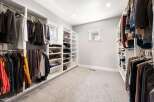 Step into this spacious walk-in closet, meticulously organized with custom shelving and ample hanging space for your wardrobe.