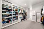 Discover ample storage in this spacious walk-in closet, featuring floor-to-ceiling shelving and multiple hanging racks to organize your wardrobe.