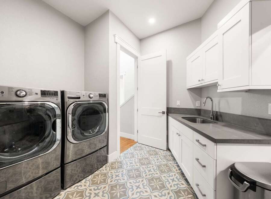 This modern laundry room features a spacious layout with a large capacity front-loading washer and dryer set.