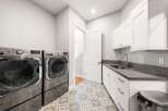 This modern laundry room features a spacious layout with a large capacity front-loading washer and dryer set.