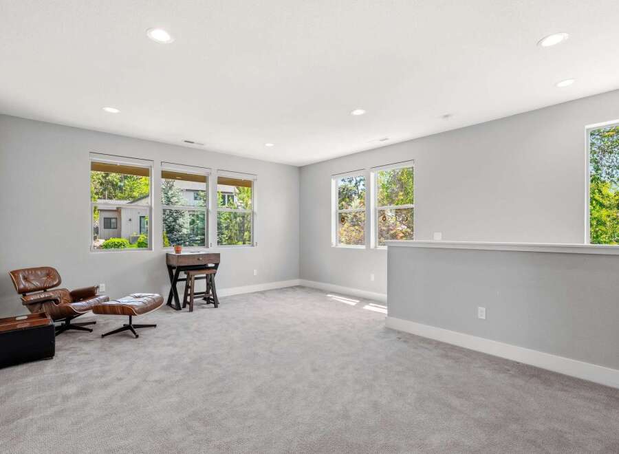 This spacious loft area offers a comfortable seating arrangement with a leather armchair and ottoman, perfect for relaxation or reading.