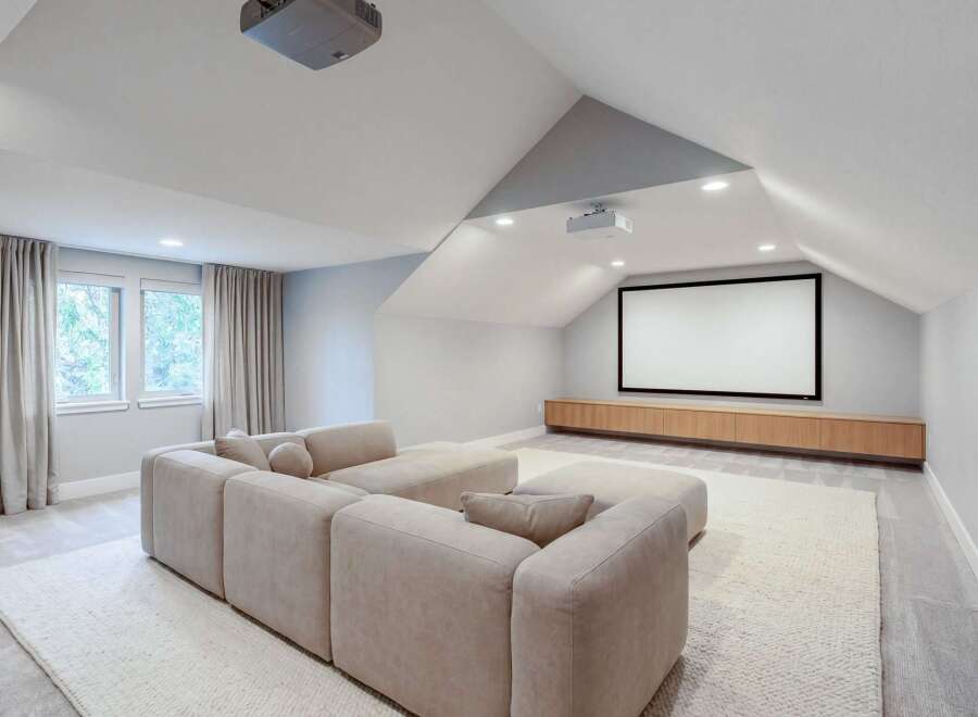 Experience cinematic bliss in this modern home theater, featuring a large projection screen and comfortable sectional sofa.