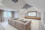 Experience cinematic bliss in this modern home theater, featuring a large projection screen and comfortable sectional sofa.