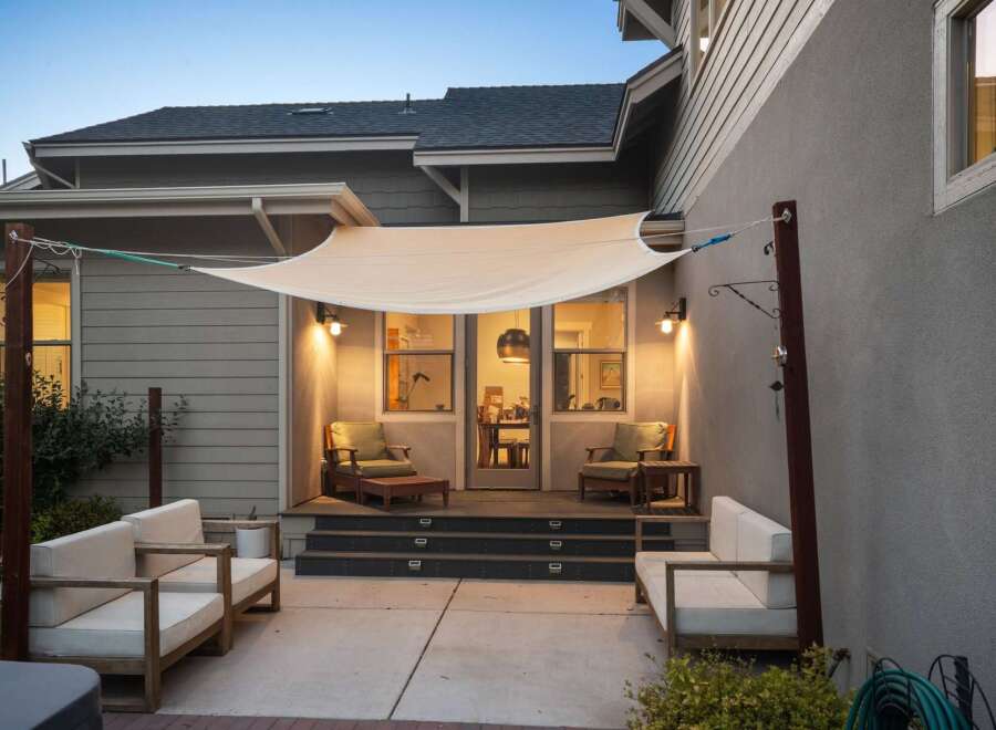 Enjoy outdoor living with this inviting patio space, featuring comfortable seating and a stylish shade sail for sun protection.