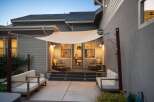 Enjoy outdoor living with this inviting patio space, featuring comfortable seating and a stylish shade sail for sun protection.