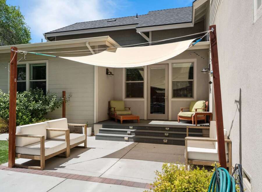 Enjoy outdoor living with this spacious patio featuring comfortable seating and a stylish shade sail.