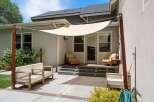 Enjoy outdoor living with this spacious patio featuring comfortable seating and a stylish shade sail.