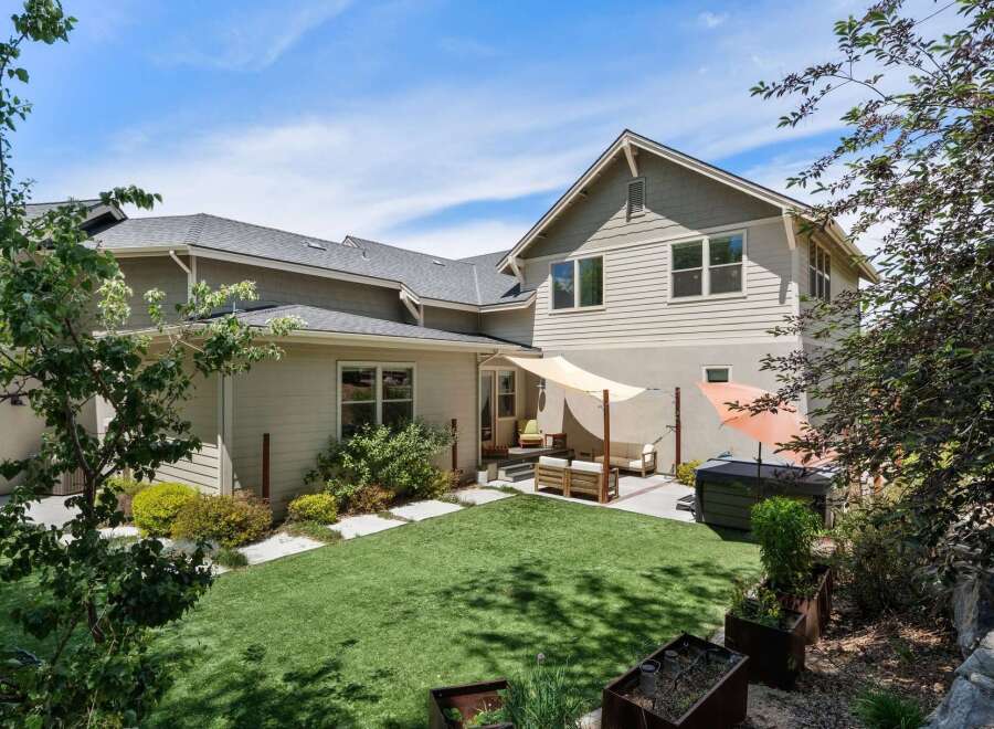 Enjoy outdoor living in this spacious backyard featuring a lush green lawn and a relaxing patio area.
