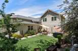 Enjoy outdoor living in this spacious backyard featuring a lush green lawn and a relaxing patio area.