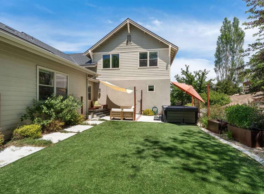 Enjoy outdoor living in this backyard oasis featuring a spacious artificial turf lawn perfect for recreation.