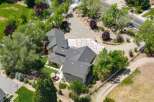 Discover this stunning property featuring a spacious, multi-level home with a dark shingle roof, nestled amidst lush greenery and mature trees.
