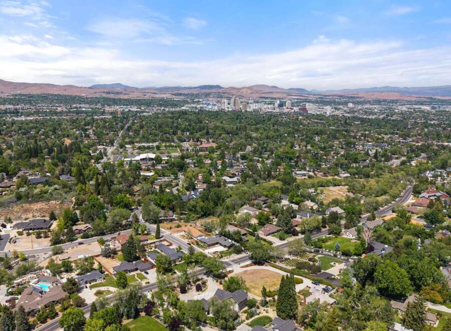Discover this stunning property nestled in a lush, tree-filled neighborhood with a vibrant cityscape in the distance.