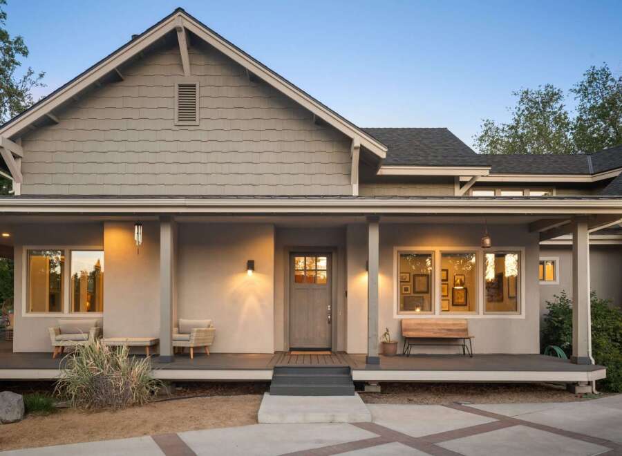 This charming home features a welcoming covered porch with comfortable seating and a rustic wooden bench, perfect for enjoying the evening air.