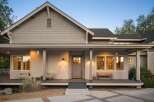 This charming home features a welcoming covered porch with comfortable seating and a rustic wooden bench, perfect for enjoying the evening air.
