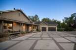 This stunning property features a spacious driveway with a unique concrete and brick paver design, leading to a large attached garage.