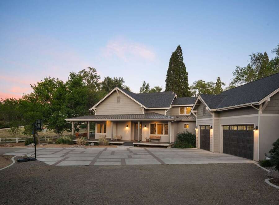 Discover this stunning modern farmhouse-style home, featuring a welcoming wrap-around porch perfect for enjoying the serene surroundings.