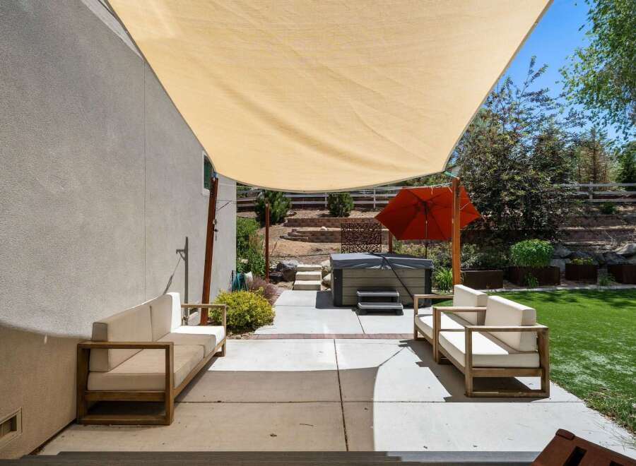 Enjoy outdoor living with this spacious patio featuring comfortable seating and a relaxing hot tub, perfect for unwinding.