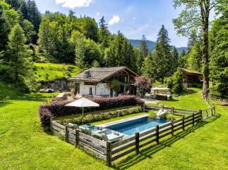 Escape to this stunning alpine retreat featuring a charming chalet-style home nestled amidst lush greenery and mature trees.