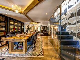 Experience luxurious living in this expansive open-plan space, featuring a grand dining area with a rustic wooden table and elegant seating, perfect for hosting.