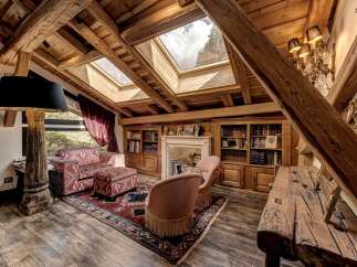 Experience rustic charm in this attic living space, featuring exposed wooden beams and a vaulted ceiling with skylights that flood the room with natural light.