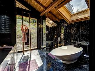 Experience ultimate luxury in this stunning bathroom featuring a freestanding soaking tub and a sleek black marble design.