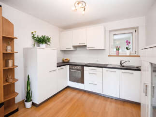 Discover this modern kitchen featuring sleek white cabinetry and a durable dark countertop.