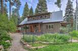 Nestled amidst tall pines, this charming home offers a serene retreat with its rustic metal roof and warm wood accents.