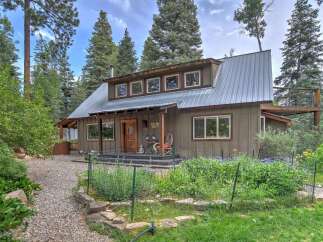 Nestled amidst tall pines, this charming home offers a serene retreat with its rustic metal roof and warm wood accents.