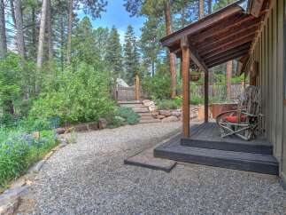 Experience rustic charm with this inviting porch, featuring a unique twig chair perfect for enjoying the serene, wooded surroundings.