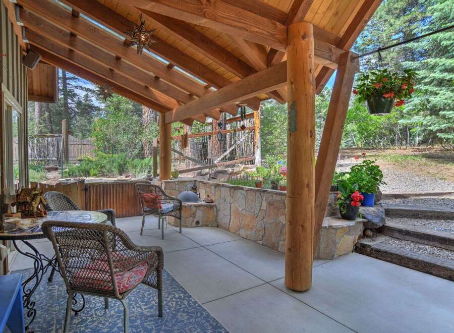 Enjoy outdoor living on this covered patio, featuring a rustic stone wall and comfortable seating.