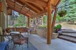 Enjoy outdoor living on this covered patio, featuring a rustic stone wall and comfortable seating.