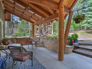 Enjoy outdoor living on this covered patio, featuring a rustic stone wall and comfortable seating.