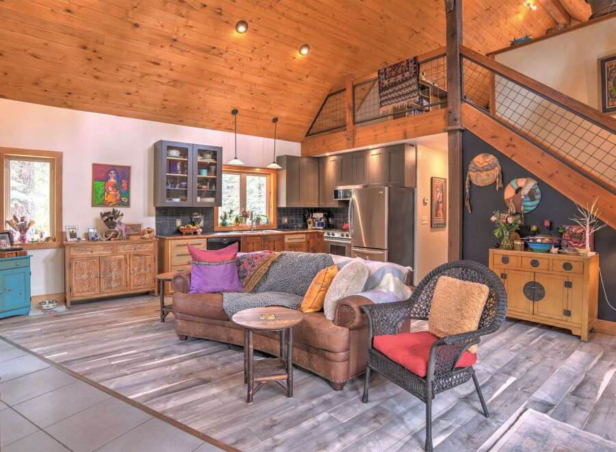 Experience rustic charm in this open-concept living space, featuring a vaulted wood-paneled ceiling and a cozy seating area.