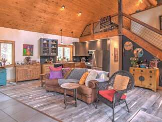 Experience rustic charm in this open-concept living space, featuring a vaulted wood-paneled ceiling and a cozy seating area.