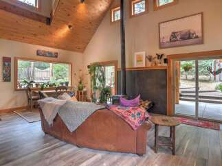 Experience rustic charm in this inviting living room, featuring a vaulted wood-paneled ceiling and a cozy wood-burning stove.