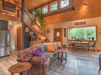 Experience rustic charm in this inviting living space, featuring a plush leather sofa adorned with colorful throws and pillows.