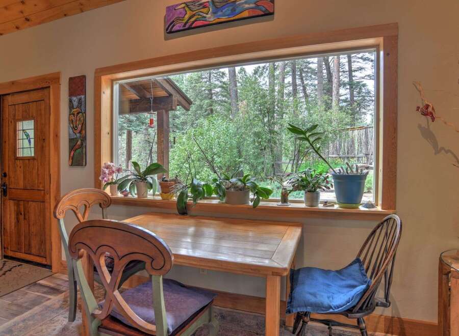 Enjoy a serene dining experience with this charming table and chairs, perfectly positioned to overlook a lush forest view.