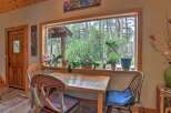 Enjoy a serene dining experience with this charming table and chairs, perfectly positioned to overlook a lush forest view.