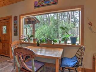 Enjoy a serene dining experience with this charming table and chairs, perfectly positioned to overlook a lush forest view.