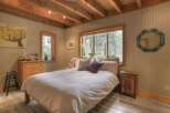 Experience cozy cabin living in this charming bedroom, featuring a comfortable bed adorned with plush pillows and a white duvet.