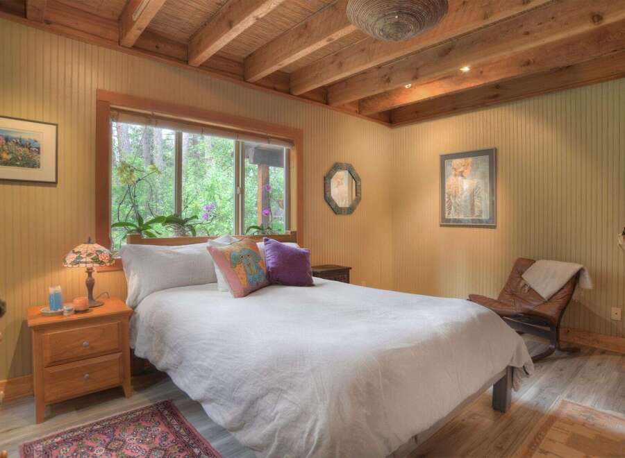 Experience serene living in this charming bedroom, featuring a cozy bed dressed in crisp white linens and accented with decorative pillows.