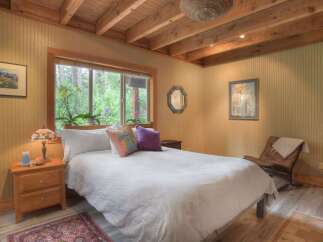 Experience serene living in this charming bedroom, featuring a cozy bed dressed in crisp white linens and accented with decorative pillows.
