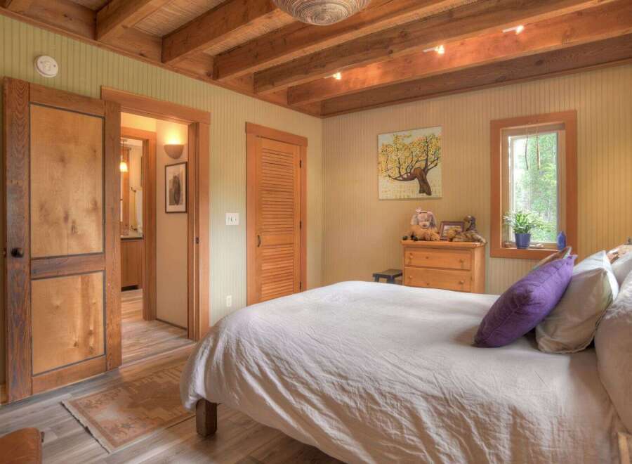 Experience rustic charm in this cozy bedroom featuring exposed wooden beams and a warm, inviting color palette.